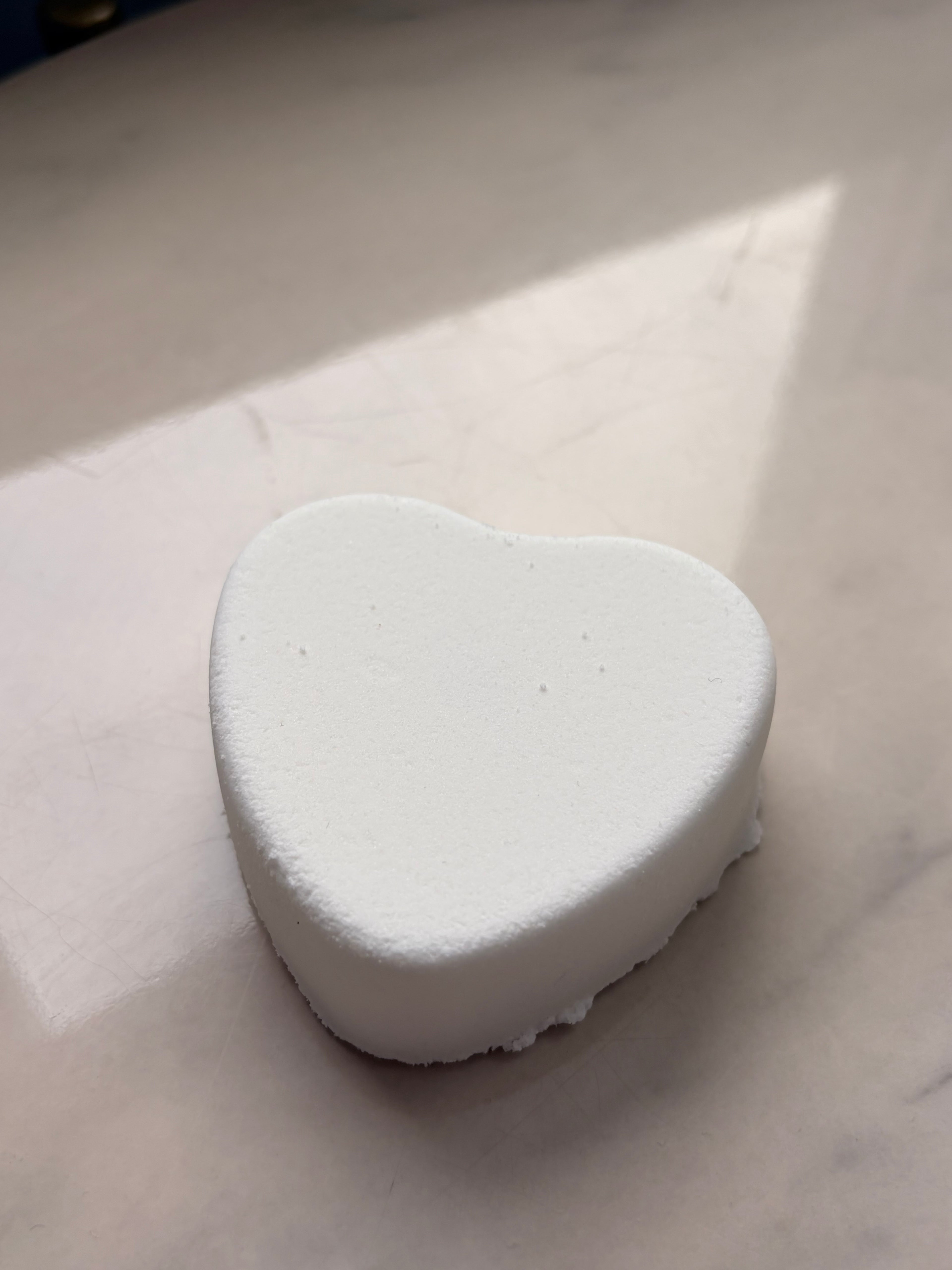 White heart-shaped bath bomb on a light gray background