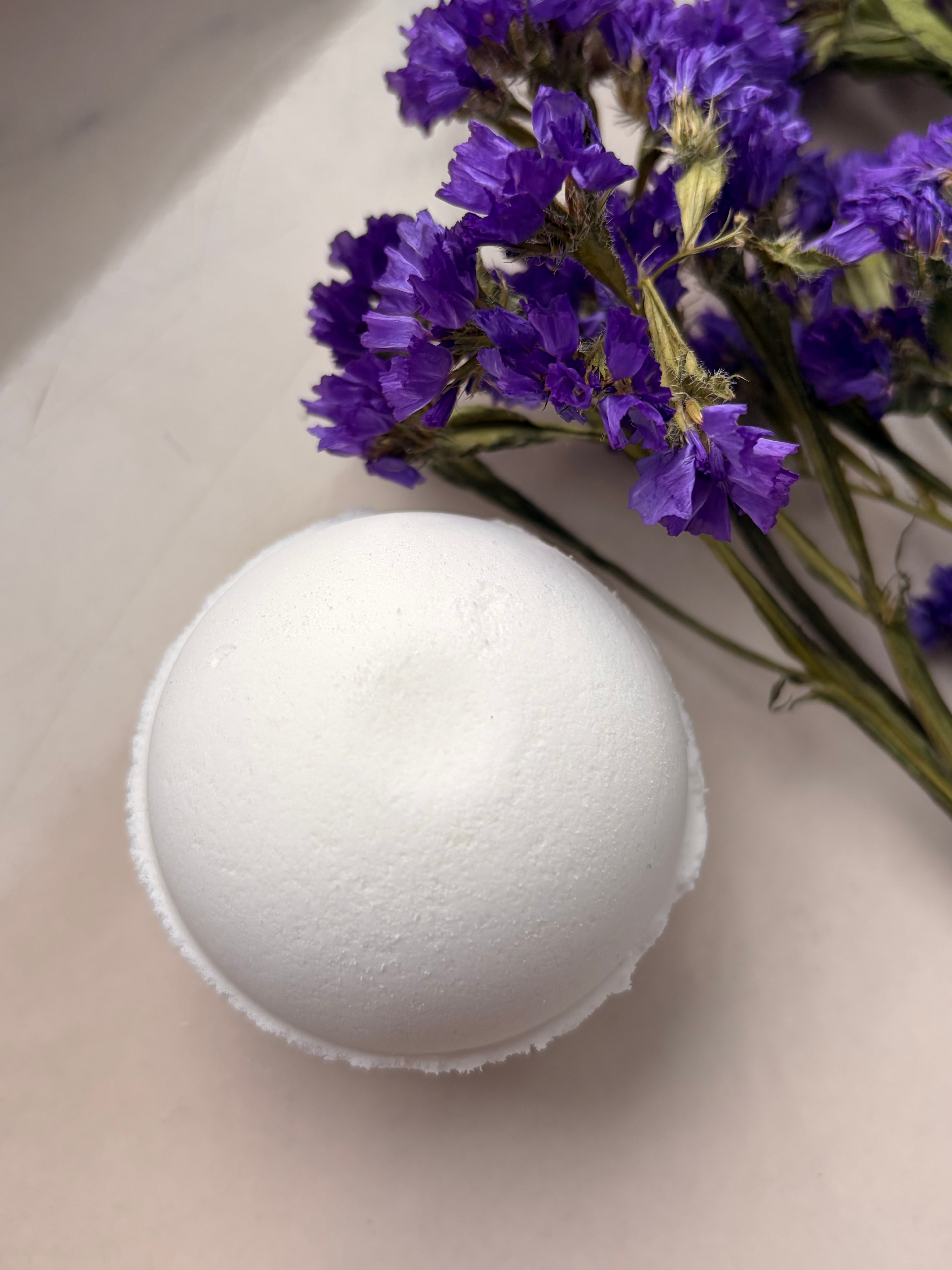 Eczema-friendly unscented bath bomb for sensitive skin, handpressed 4.1 oz sphere with a hidden toy surprise, beige surface purple flowers