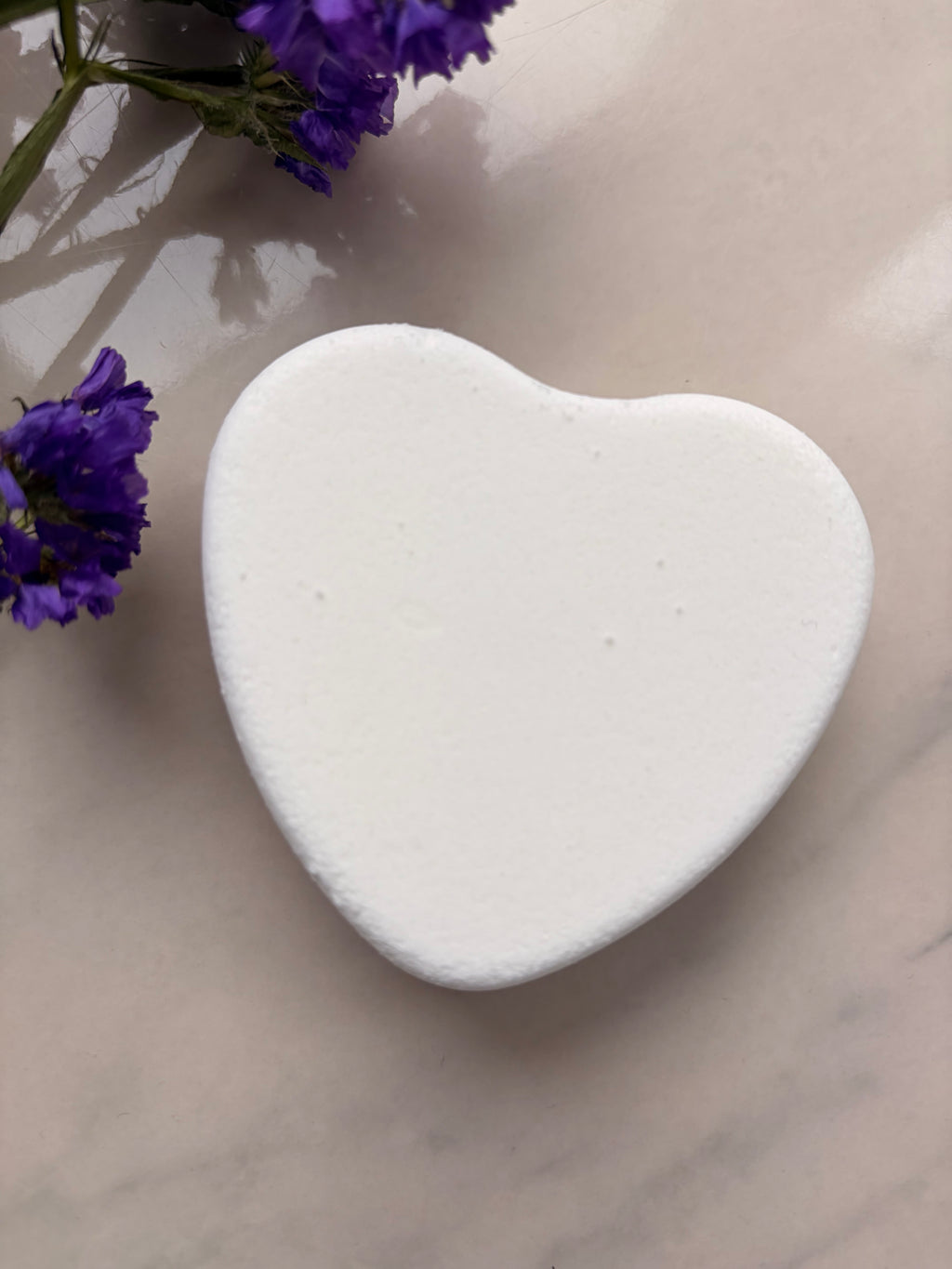 White heart-shaped object on a textured surface with purple flowers eczema and sensitive skin friendly